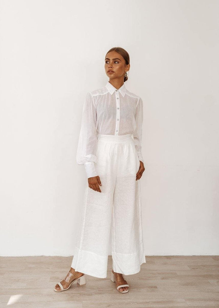 woman in a linen shirt is wearing also white trousers resembling traditional bohemian style